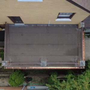 Aerial view of flat roof deck on brick home with smooth roofing membrane, updated railings, and new copper gutters.