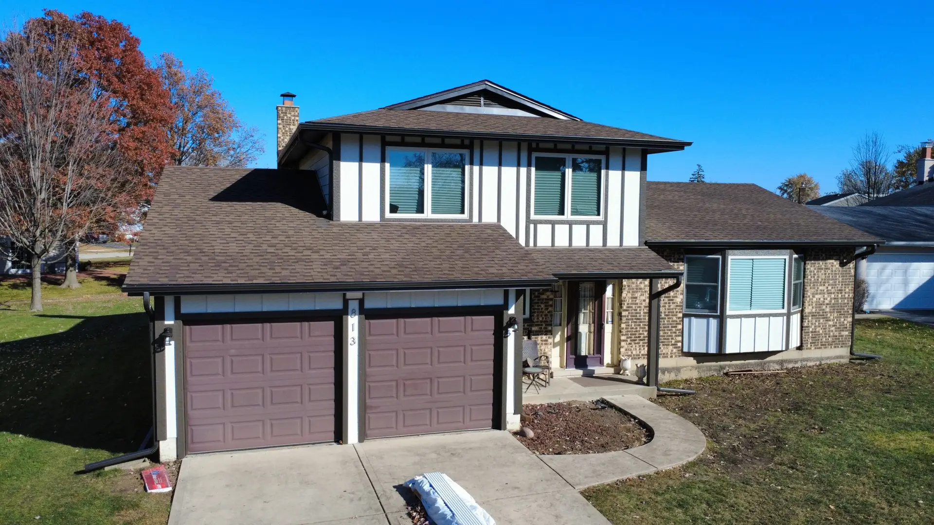 Front drone view of a completed brown shingle roof on a Tudor style two story home