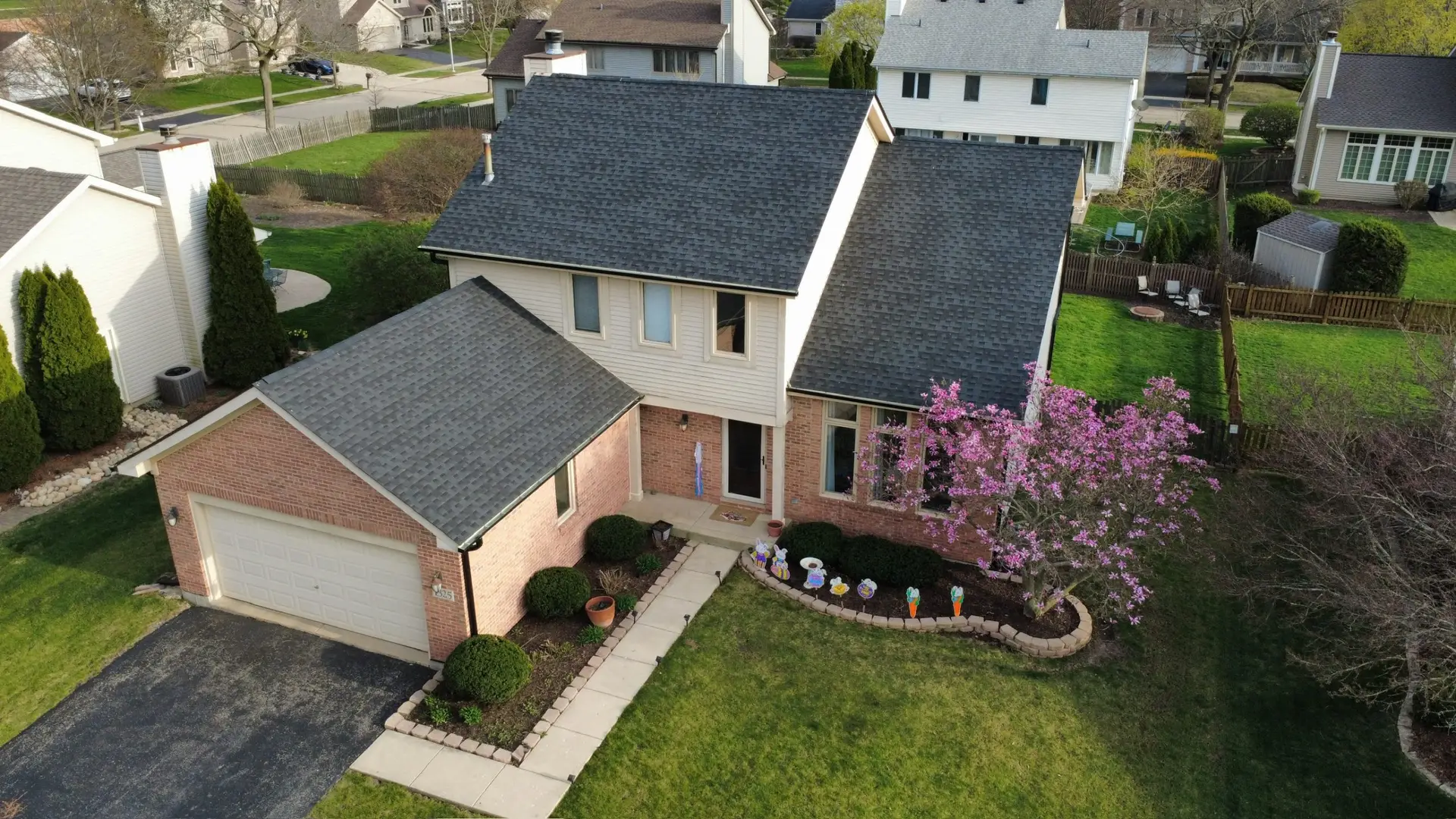 New charcoal shingle roof on a brick two story home framed by a magnolia tree