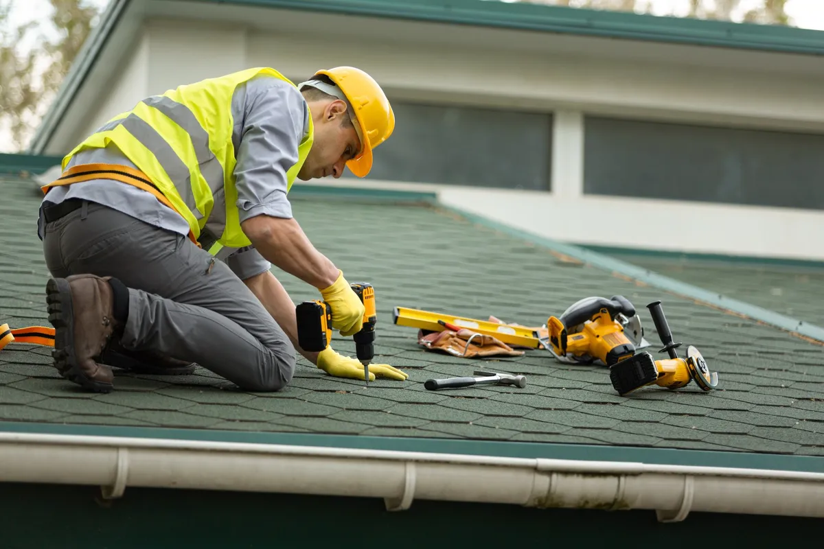 A roofer in protective gloves works on a roof, emphasizing the importance of professional roofing services.