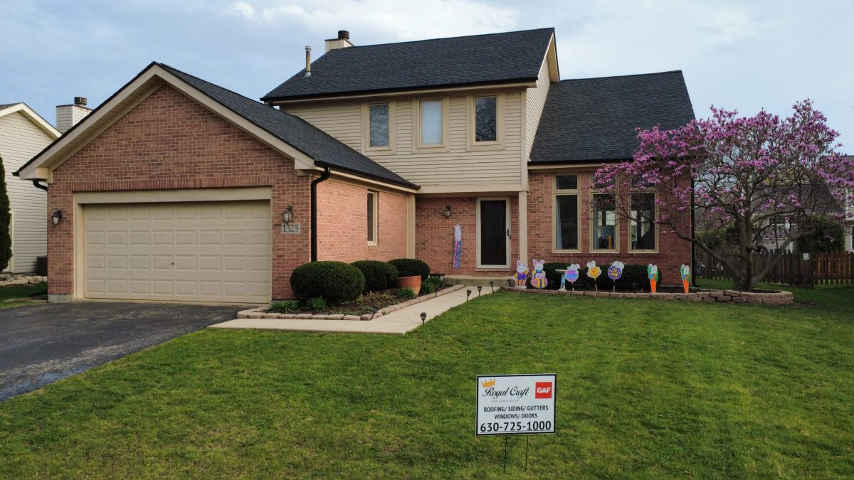 Ground view of a completed charcoal roof on a brick two story home with a Royal Craft GAF yard sign