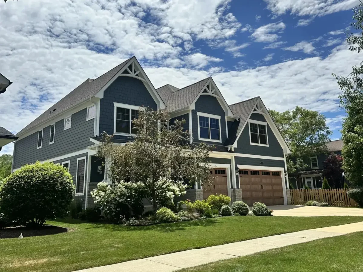 Craftsman-style home with navy blue lap and shake siding, white gable trim, and dark wood three-car garage doors