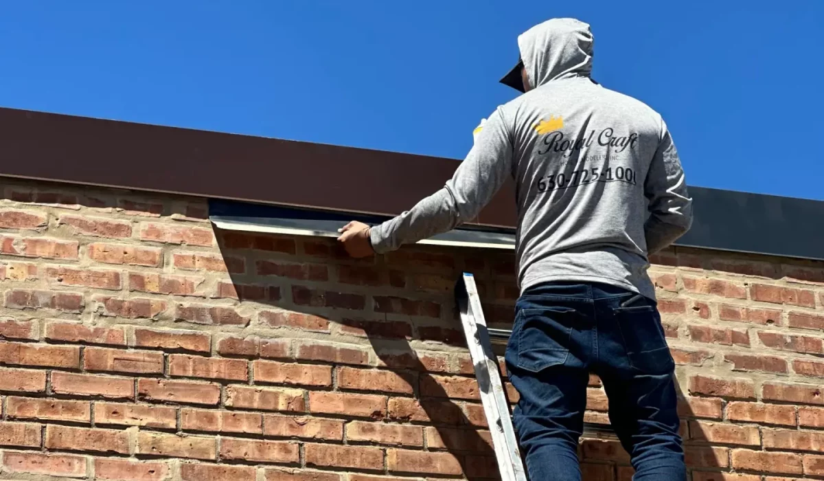Contractor installs flashing to prevent water intrusion and extend roof life on a brick commercial building.