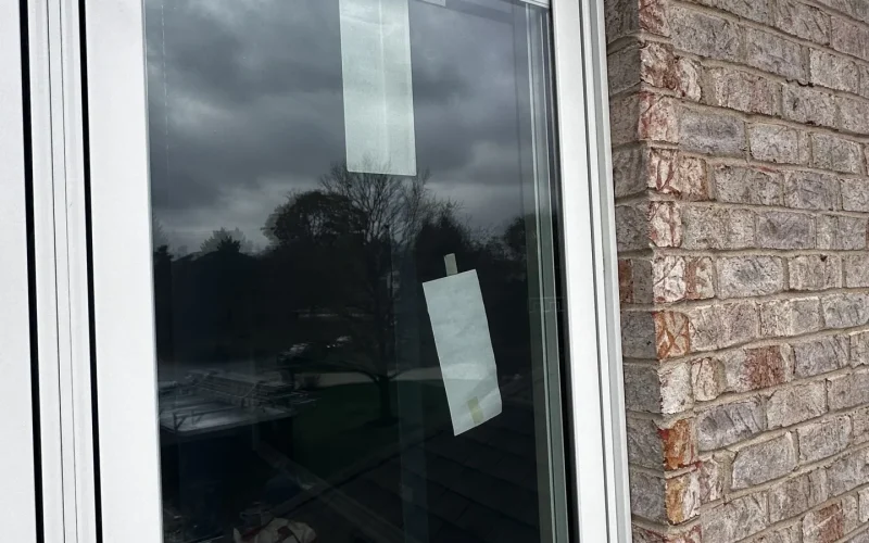Close-up of a newly installed white-trim Pella window on a brick home exterior.
