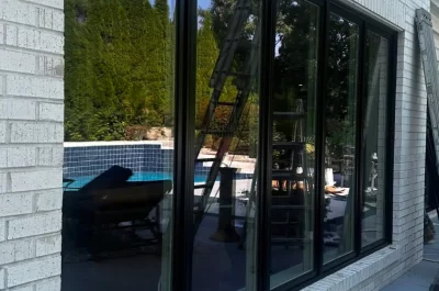 Modern black-framed windows reflect backyard pool, signaling recent window replacement for improved home energy efficiency.