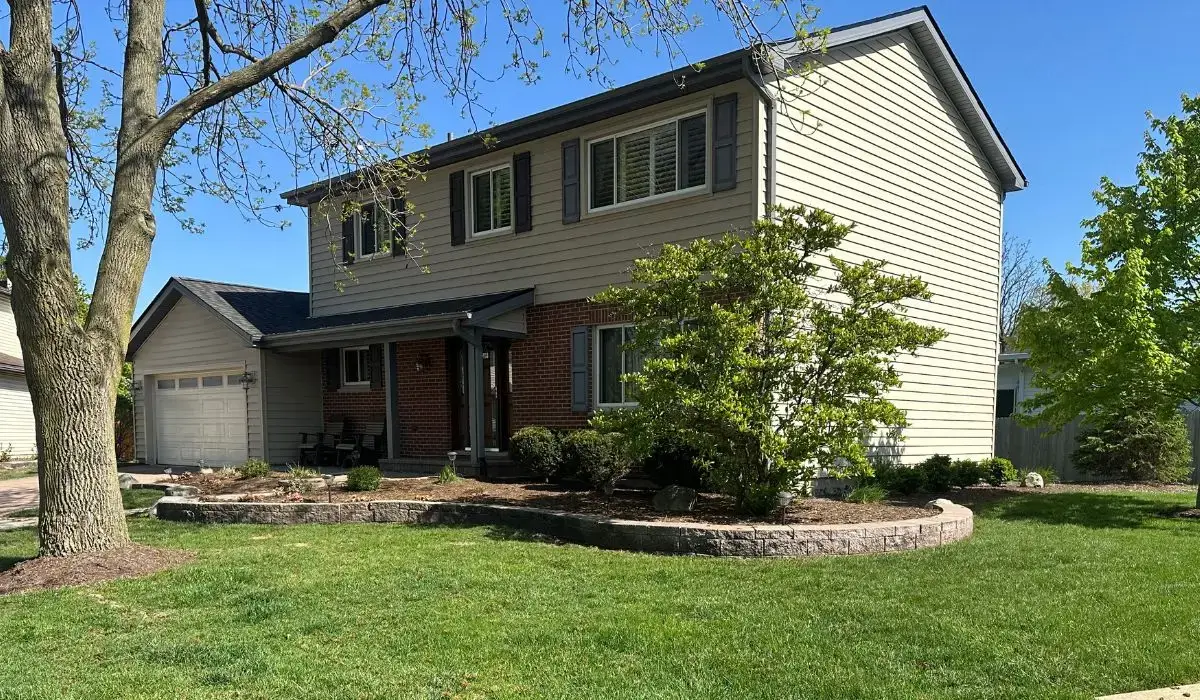 Front entry door of a two-story Hinsdale home surrounded by landscaping, shutters, and neutral exterior siding.