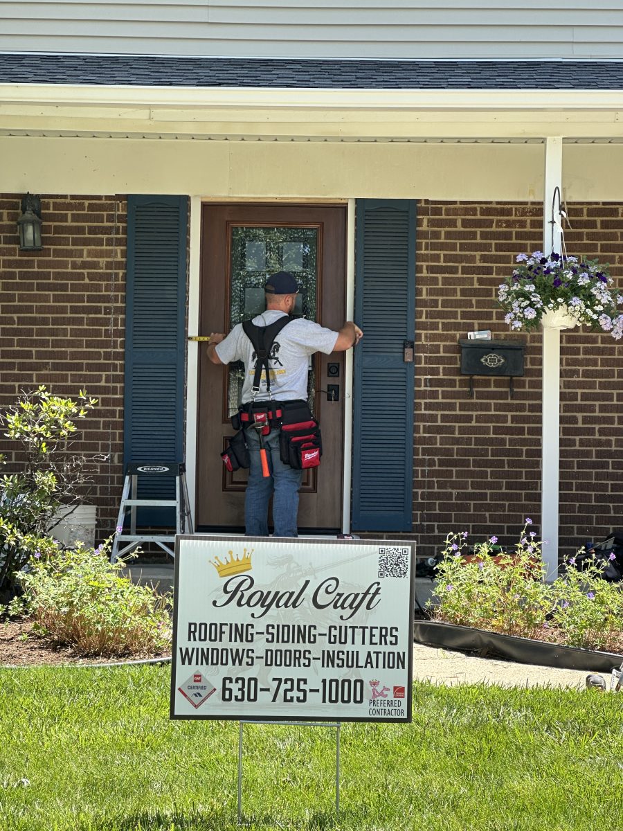 Royal Craft technician measuring a front entry door with a Royal Craft yard sign in the foreground
