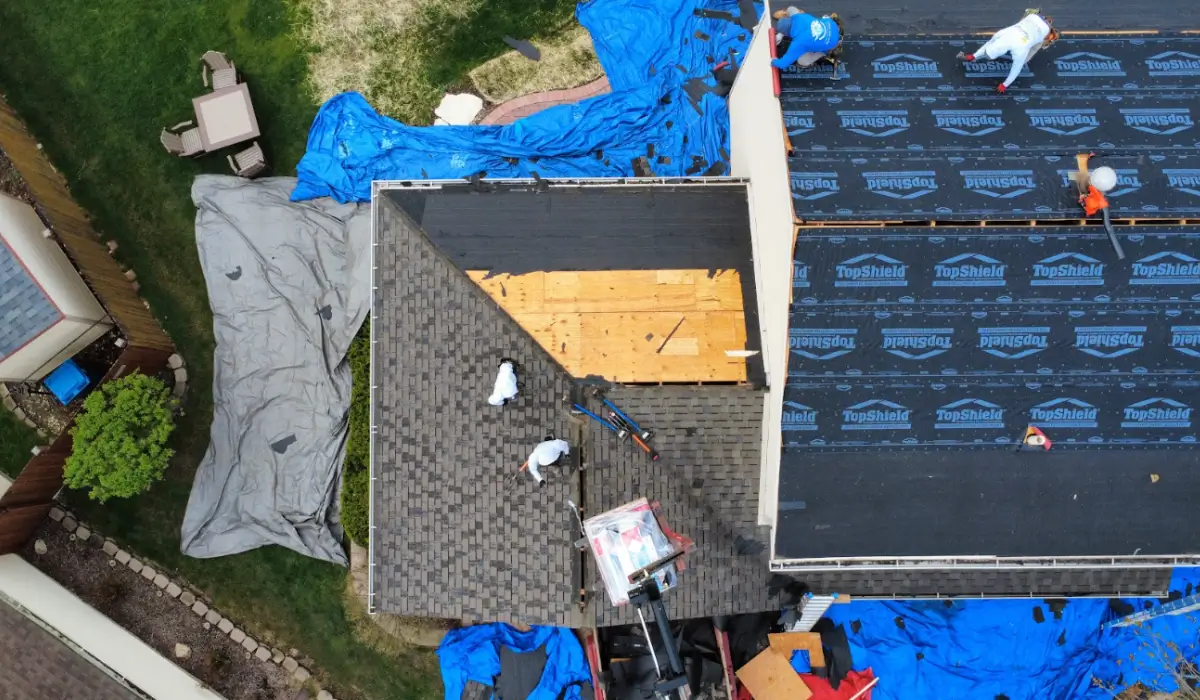 Local roofers installing shingles on residential rooftop using safety gear and materials in Downers Grove neighborhood.
