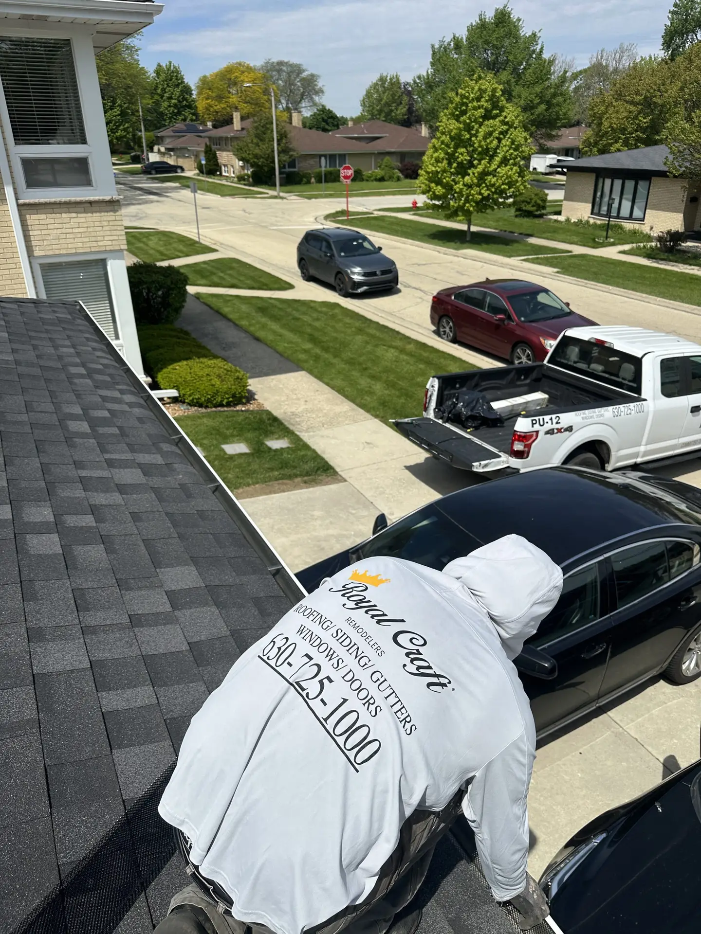 Royal Craft technicians working on a mansard roof and gutters above a driveway