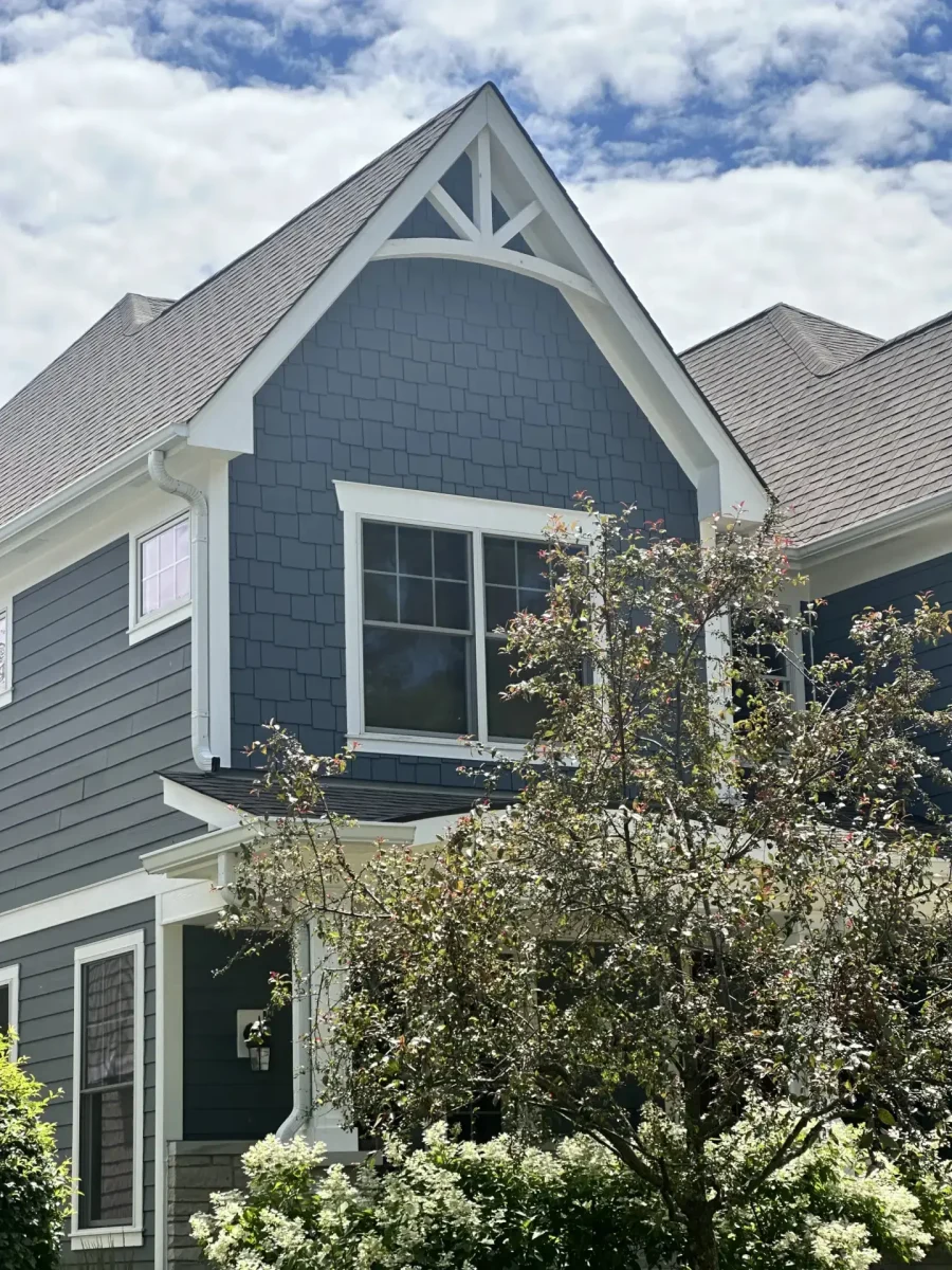 Close-up of navy blue shake siding with white peaked gable trim on a two-story craftsman home