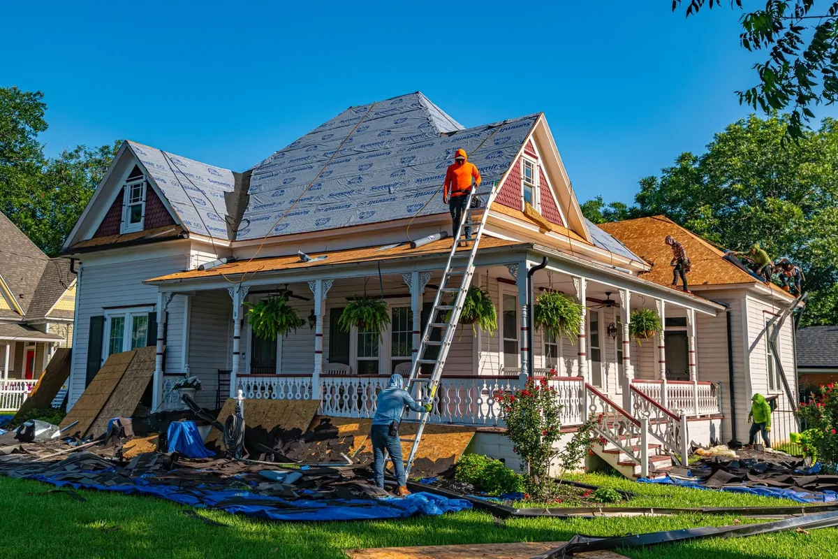 Roofers working on replacing the roof of a historic home, highlighting the importance of maintenance.