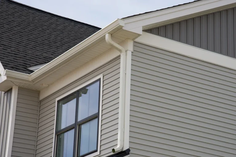A newly installed metal gutter drain pipe, showcasing quality home exterior improvements.