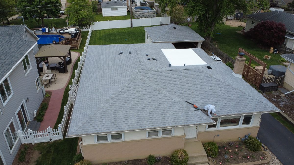 Royal Craft roofer finishing gutter edge detail work on a new gray shingle ranch roof
