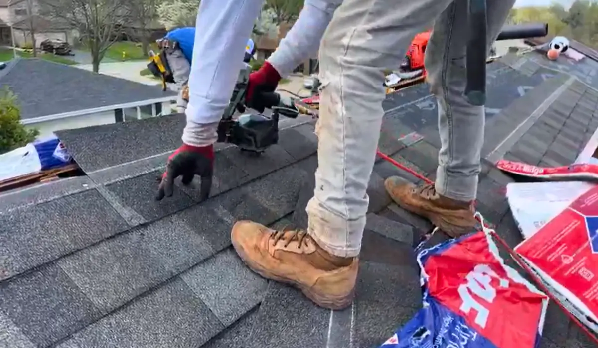 Professional roofer installing asphalt shingles to replace your roof using nail guns and starter strip.
