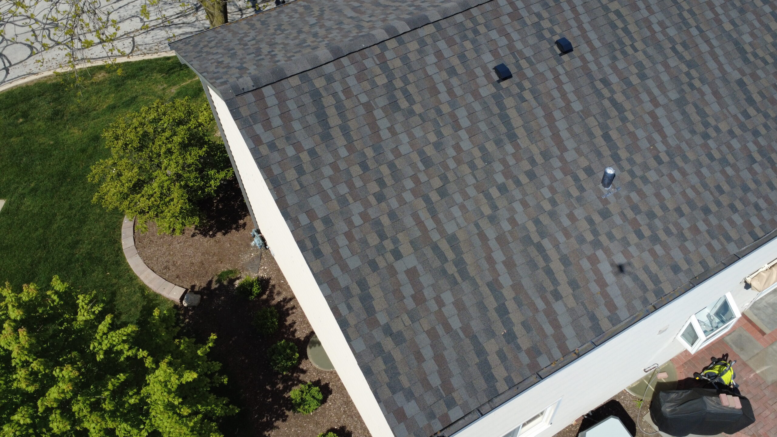 Close-up aerial view of a newly installed multi-tone asphalt shingle roof on a two-story home.