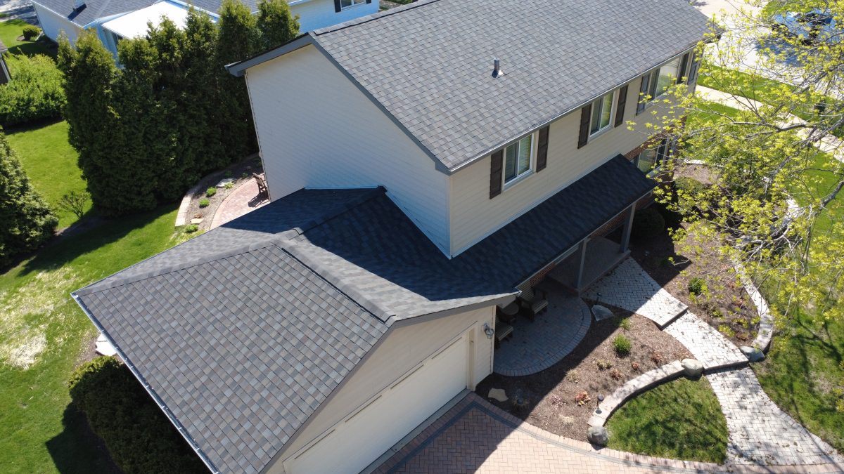 Close-up aerial view of a newly installed multi-tone asphalt shingle roof on a two-story home.