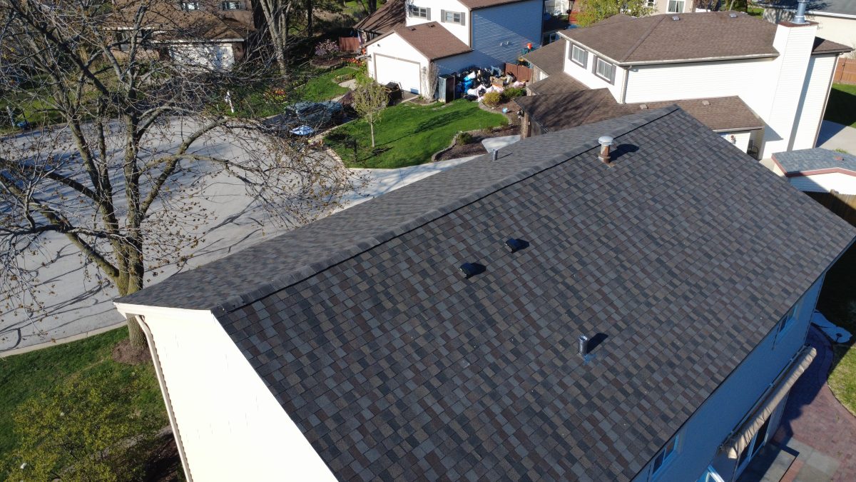 Aerial side view of a two-story home with a newly installed dark gray asphalt shingle roof in Downers Grove.