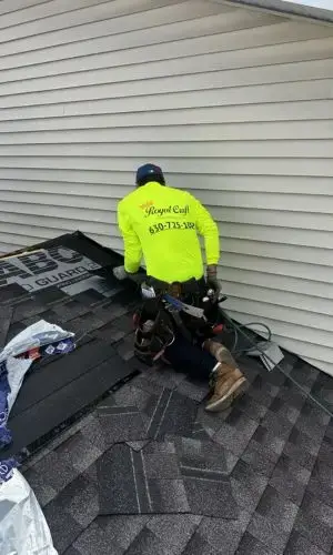 Roofing company crew in Downers Grove installing shingles near siding wall