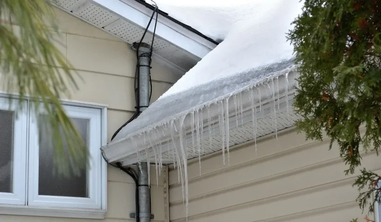 Snow and ice buildup with visible ice dams causing roof and gutter strain on residential home.